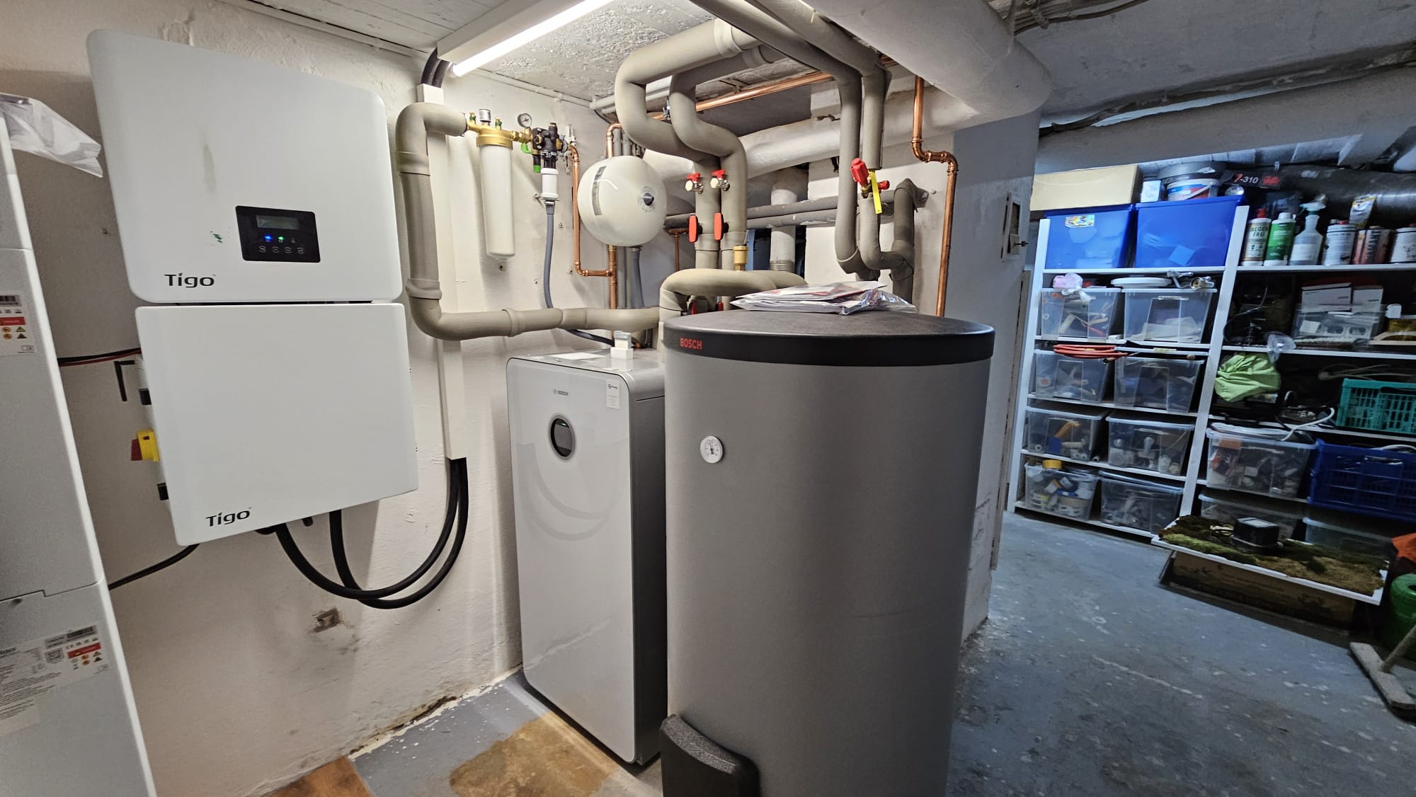 Ein Technikraum mit mehreren Komponenten einer Heizungs- und Wärmepumpenanlage, darunter Geräte von Tipo und Bosch.